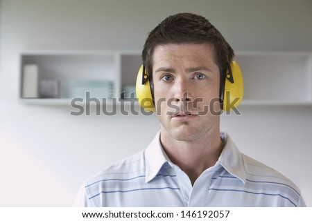 Closeup portrait of a young man wearing ear protectors in office