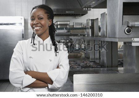 Portrait Of A Smiling Female Chef With Hands Crossed In The Kitchen