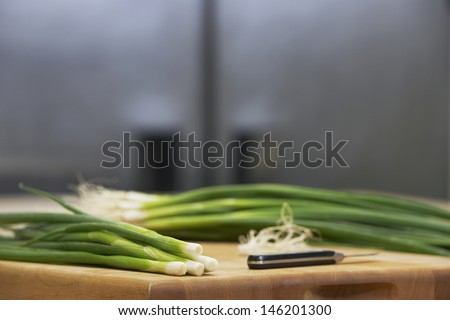 Closeup of fresh spring onions and knife on chopping board