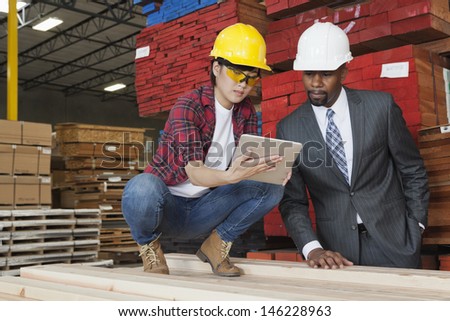 Female industrial worker showing something on tablet PC to male engineer