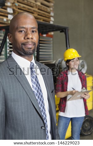 Portrait of confident African American male businessman with female worker standing in background