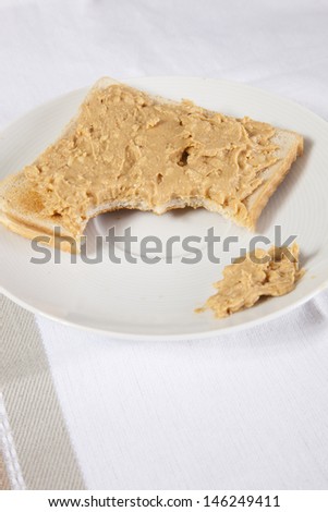 Peanut butter on slice of bitten bread