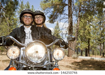 Senior couple riding motorcycle through a forest