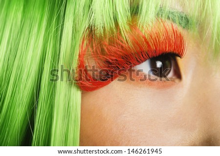 Extreme close-up of young woman\'s face with false eyelashes and green wig