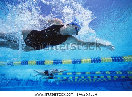 Professional female swimmers swimming in pool