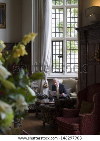 Mature businessman sitting on antique furniture and reading