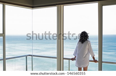 Rear view of young woman looking at sea view from balcony at resort