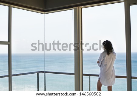 Rear view of young woman looking at ocean view from balcony at resort