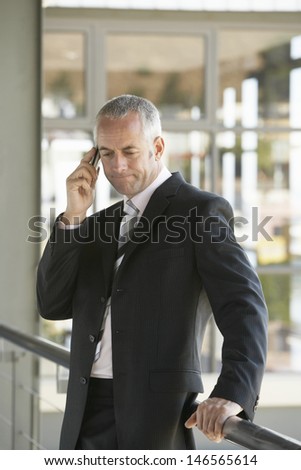 Serious middle aged businessman using cell phone in office