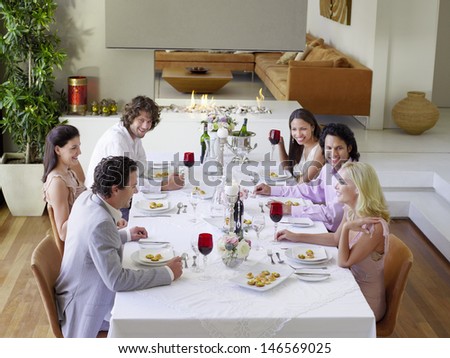 Group of multiethnic friends drinking and socialising at dinner party
