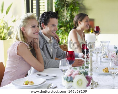 Beautiful young couple with arm around at dinner party