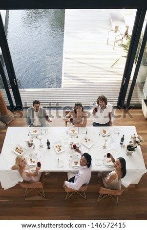High angle portrait of multiethnic friends toasting wine at dinner party