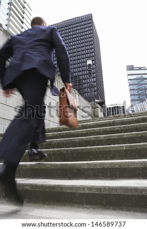 Full Length Rear View Of A Businessman With Briefcase Ascending Steps