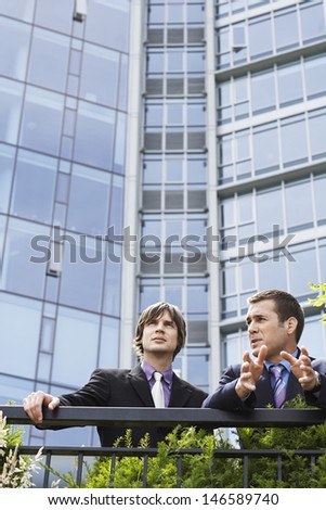 Two young businessmen talking outside office building