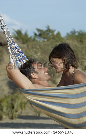 Side view of a young couple in hammock smiling