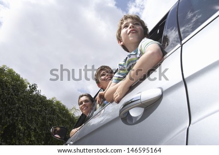 Low angle view of mother and two boys leaning through car window