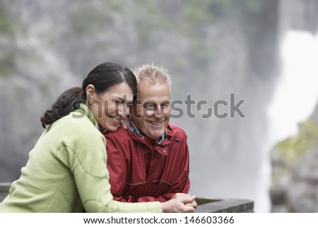 Happy middle aged man and woman looking at view against blurred background