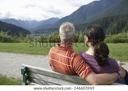 Rear view of a middle aged couple sitting on bench and looking at view