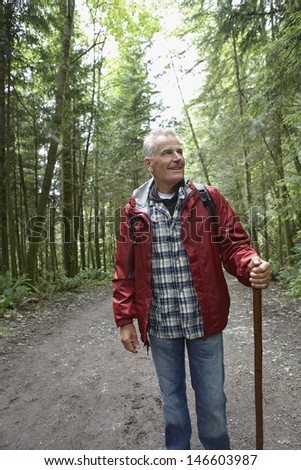 Smiling mature man walking in the forest path
