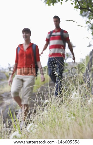 Blurred young couple walking with backpacks in countryside