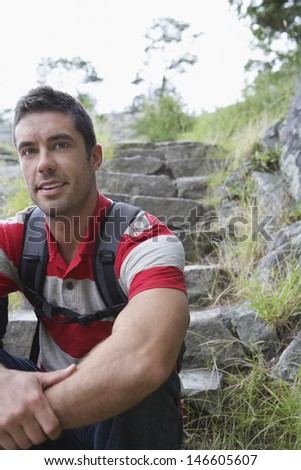 Relaxed young man sitting on steps in countryside