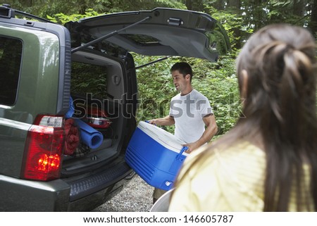 Young man loading car in the forest