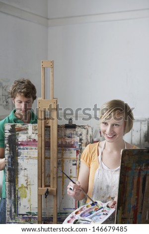 Young male and female students painting at easels in art class