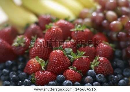 Closeup of fresh strawberries piled up on blackberries