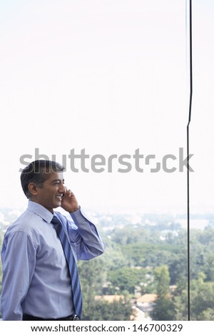 Side view of happy middle aged businessman using cell phone