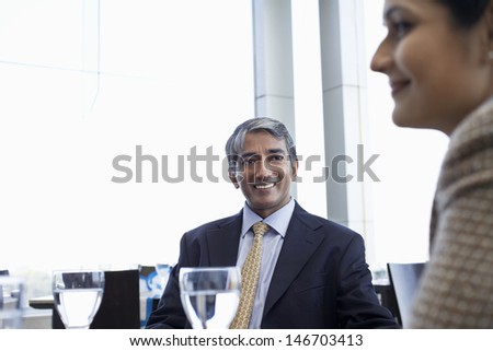 Happy middle aged businessman with female colleague in restaurant