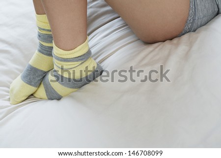 Low section of woman wearing socks lying in bed