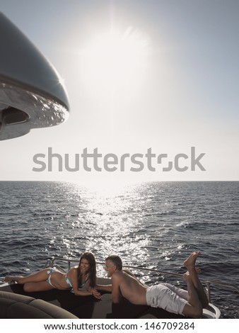 Couple lying on yacht\'s edge by sea on a sunny day