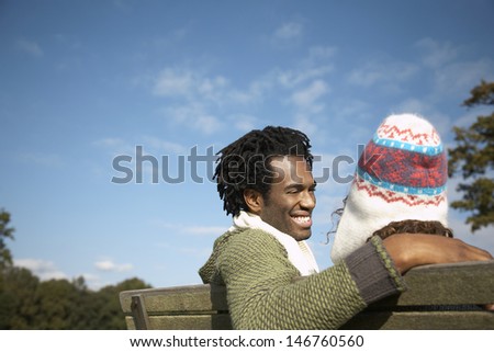 Happy young man looking at woman while sitting on park bench