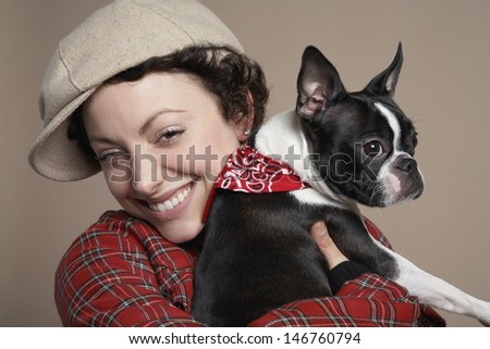 Closeup portrait of smiling young woman holding French Bulldog on colored background
