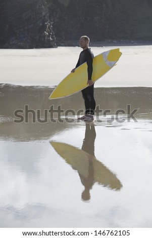 Full length side view of man carrying surfboard on beach