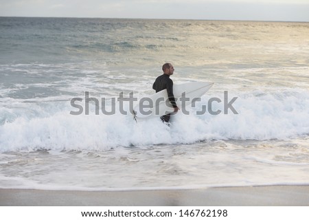 Male surfer with surfboard walking towards sea