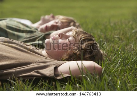 Side view of three young boys relaxing on grass