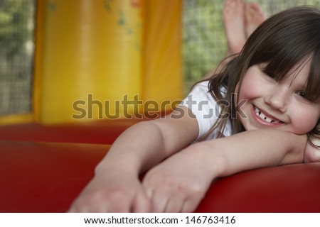 Closeup portrait of cheerful little girl lying in bouncy castle