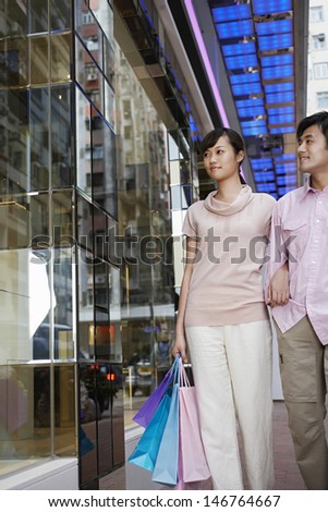 Young couple with shopping bags looking at window display