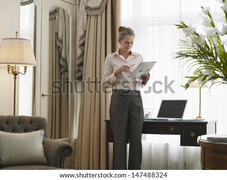 Middle aged businesswoman reading document in home office