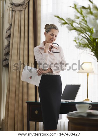 Thoughtful middle aged businesswoman with document in home office