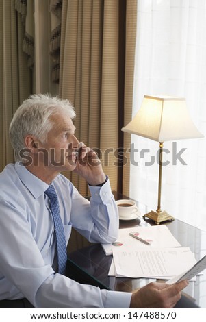 Side view of a middle aged businessman on call at home desk