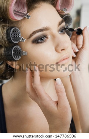 Closeup of a hand applying mascara to female model