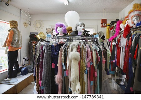 View of clothing and wigs in a crowded second hand store