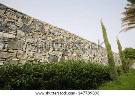 View of hedge in front of stone wall against the sky