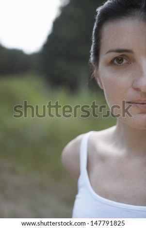 Closeup portrait of a cropped woman in tank top against blurred landscape