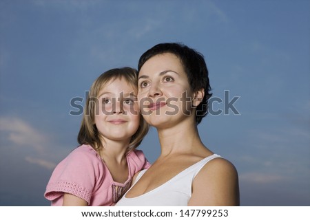 Young mother carrying daughter against the sky