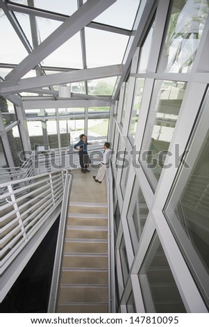 Elevated view of a male and female business executive talking in office stairwell