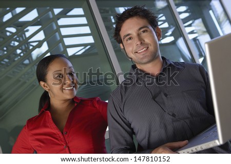 Portrait of a smiling businessman using laptop with female colleague