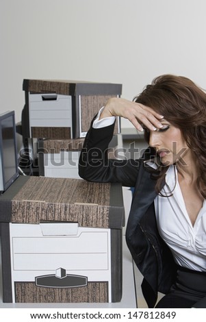 Stressed businesswoman and moving boxes at office desk